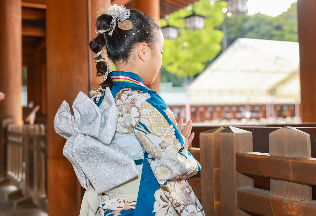 七五三の参りで、緑の和装に白い結び帯をした女の子が橿原神宮の本殿へ手を合わせている様