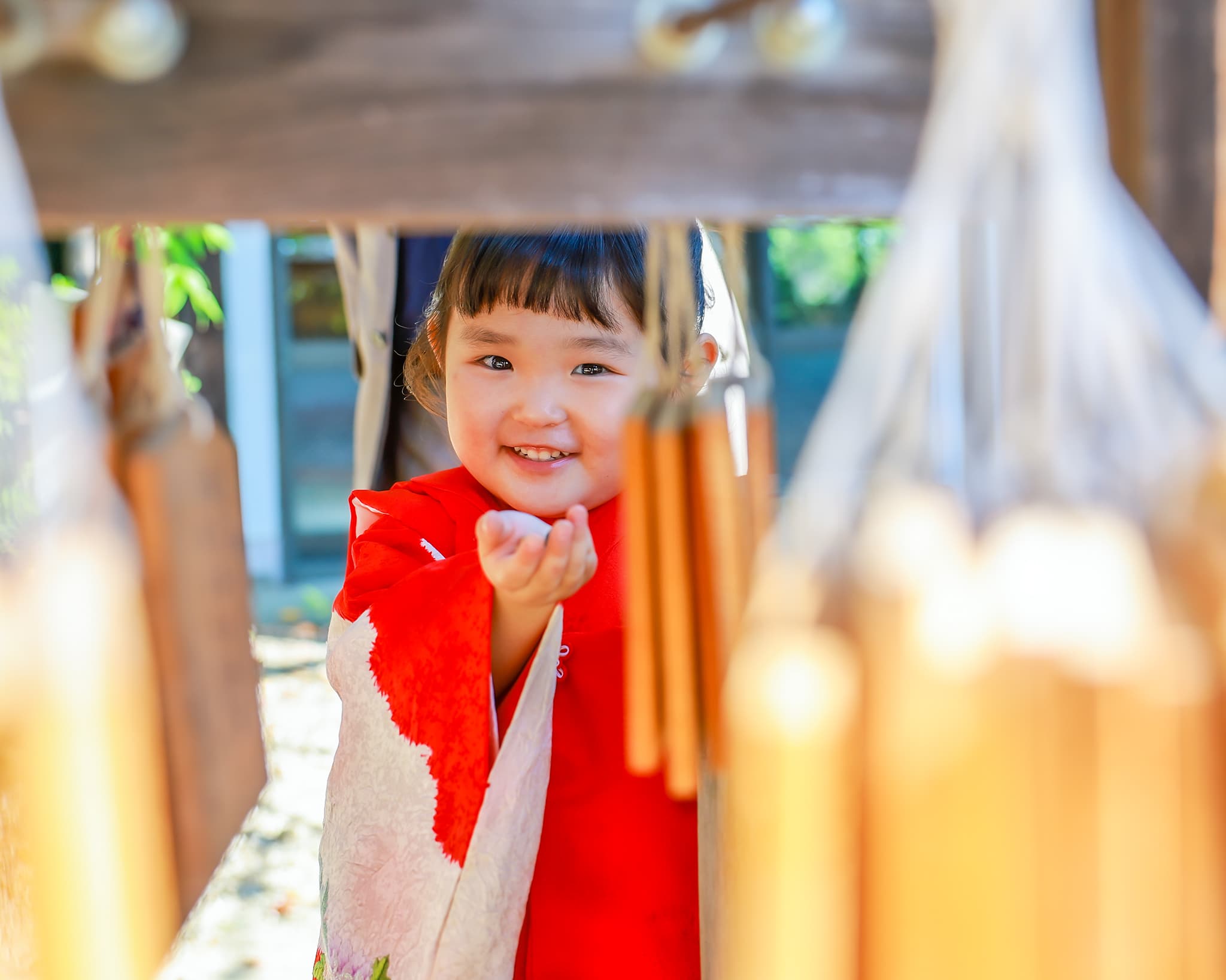 道明寺天満宮で七五三参りの３歳の女の子が絵馬の間から笑顔を見せている