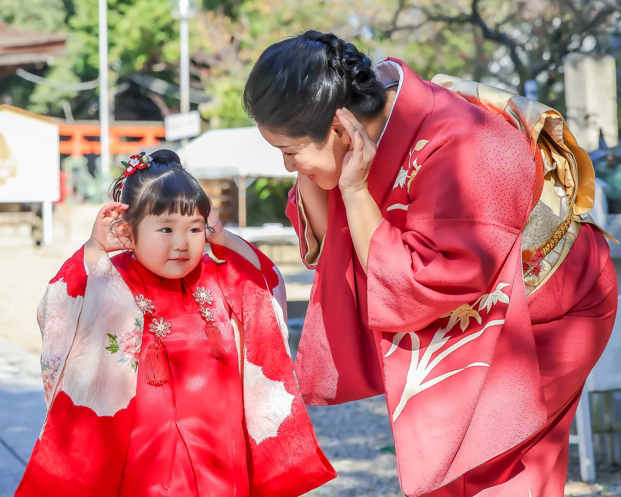 七五三参り　赤い和装の３歳女の子と赤い和装の母が耳に手を添えてよく聞こえる様に小鳥の鳴き声を良く聞こえるようにいている様