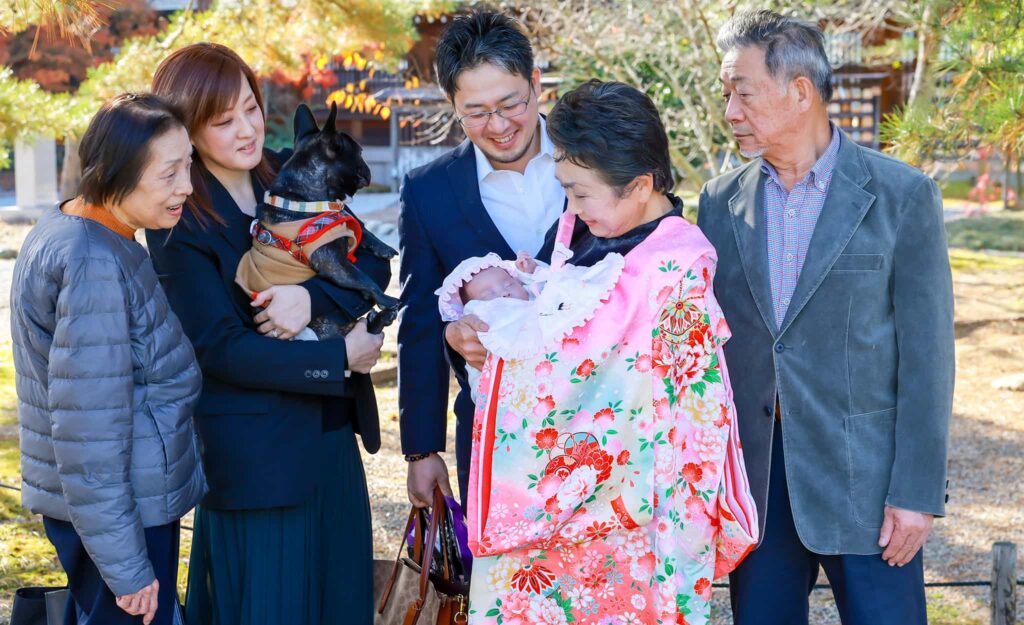 橿原神宮でお宮参りをした女の子が祖母に抱かれその周りで家族が微笑ましく見守っている様